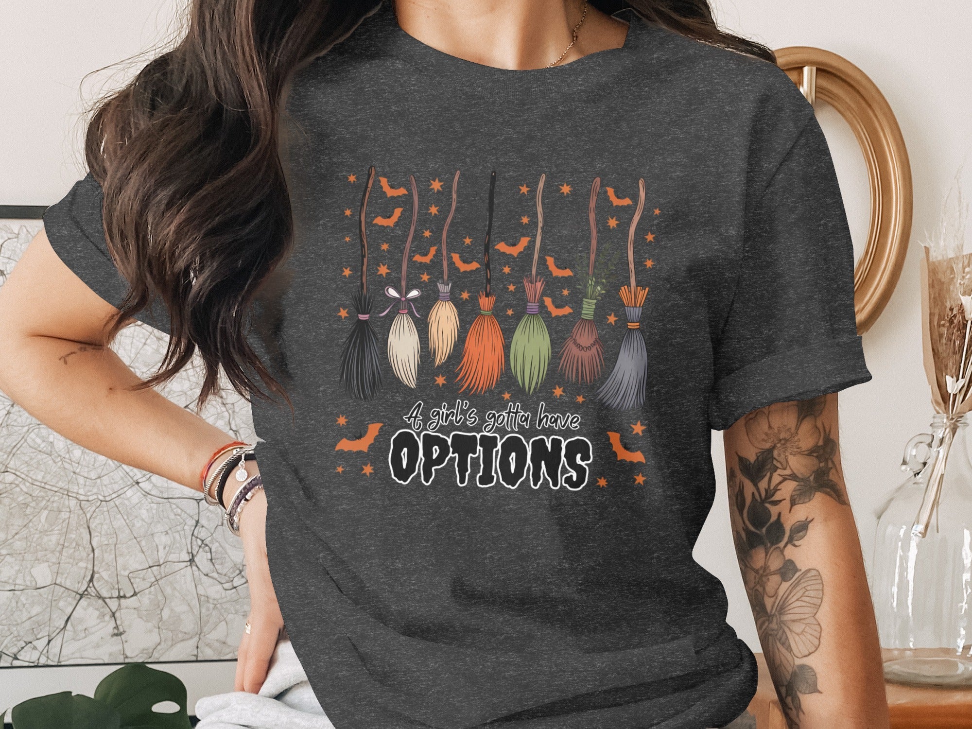 T-shirt with brooms, bats, stars, and text that reads "A girl's gotta have OPTIONS".