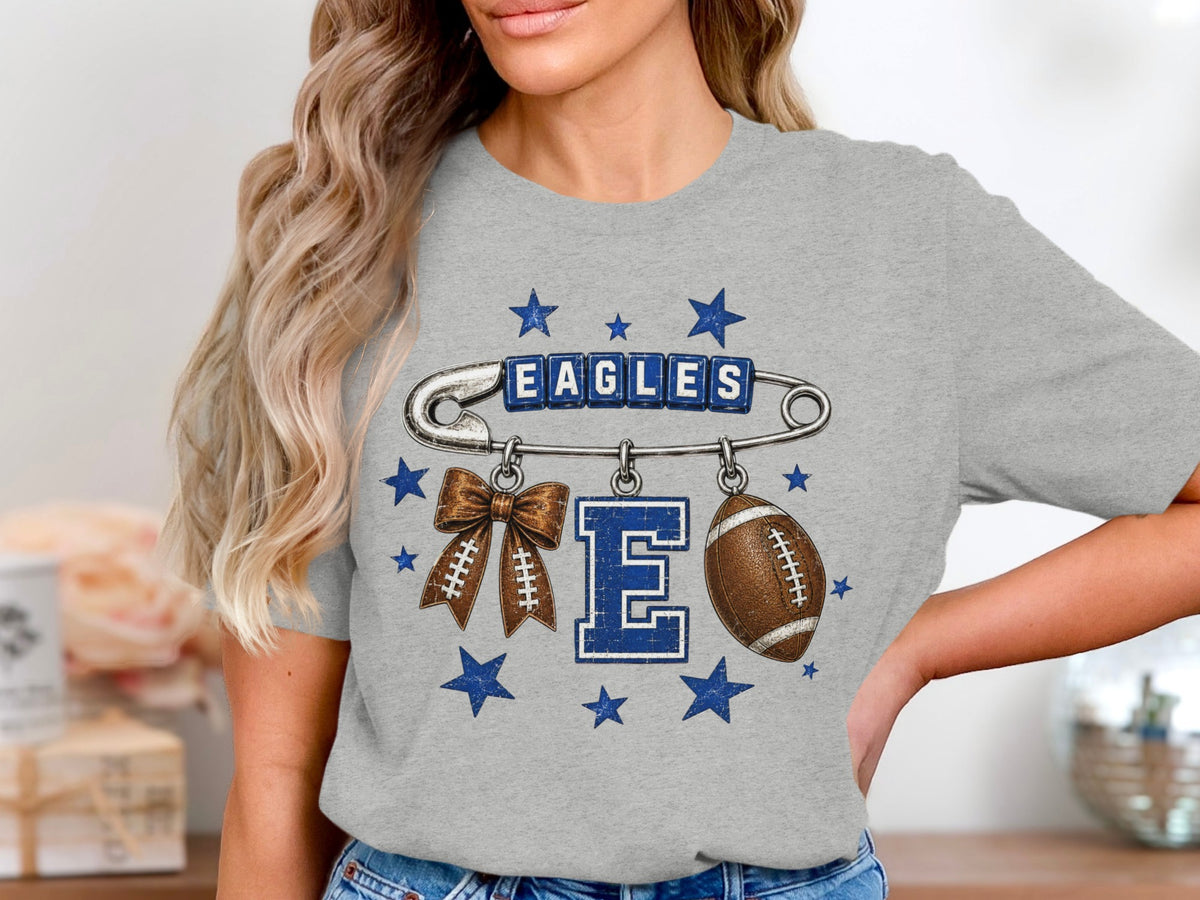 Grey t-shirt with Eagles text, safety pin, football bow, E, and football.