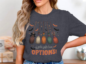 Dark grey t-shirt features five decorative brooms, stars, bats, and text saying "A girl's gotta have OPTIONS!".