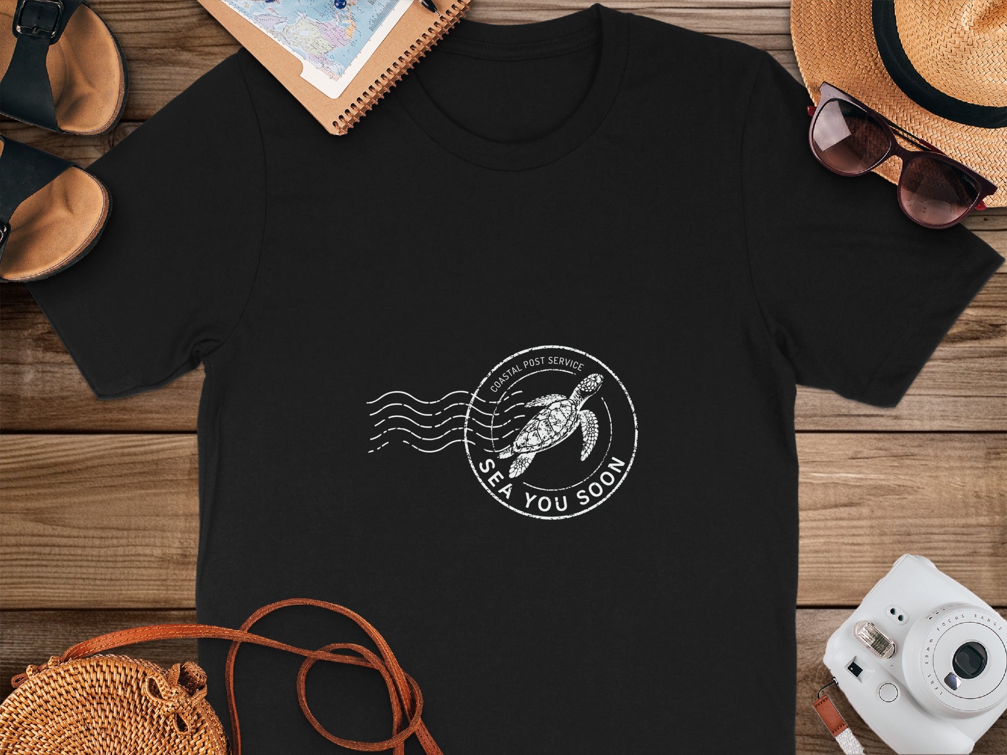 Black t-shirt with a white stamp design featuring a sea turtle and "SEA YOU SOON".