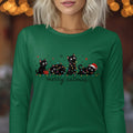 A person wearing a green long-sleeved shirt with a festive graphic of black cats and fairy lights.
