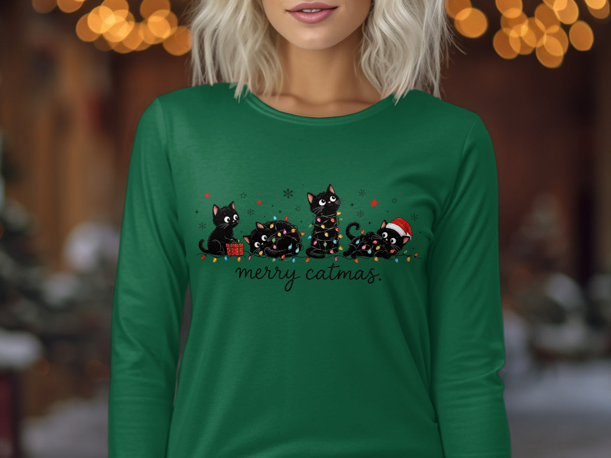 A person wearing a green long-sleeved shirt with a festive graphic of black cats and fairy lights.