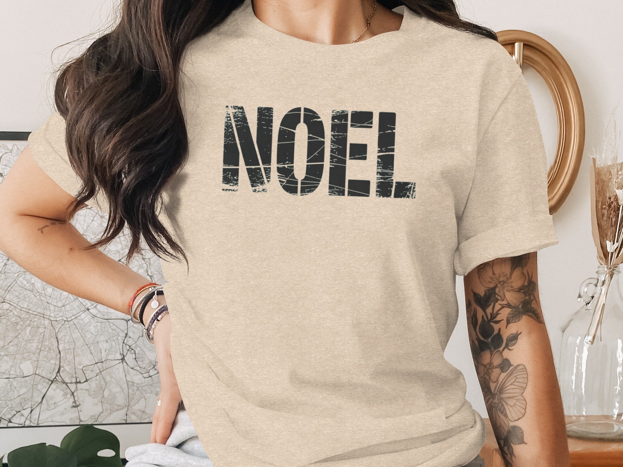 Light beige t-shirt with distressed black "NOEL" graphic print.