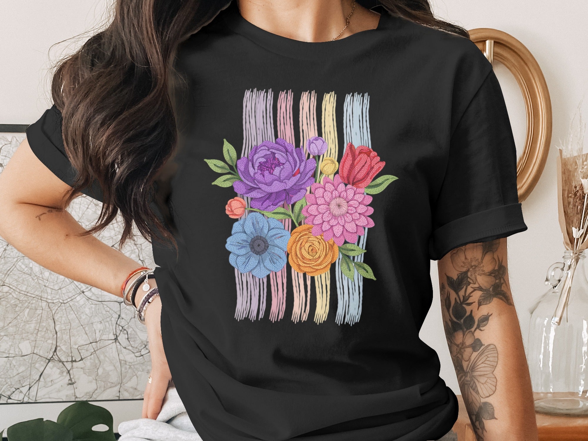 Black t-shirt with colorful floral embroidery and pastel stripes.