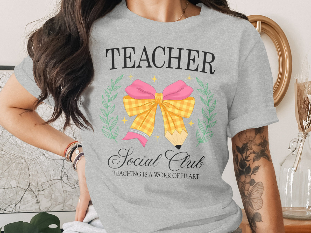 Grey t-shirt with "Teacher Social Club" text and a pencil-shaped bow graphic.