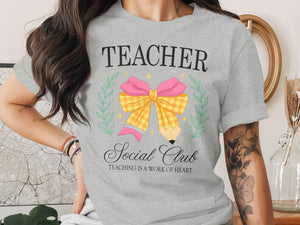 Grey t-shirt with "Teacher Social Club" text and a pencil-shaped bow graphic.