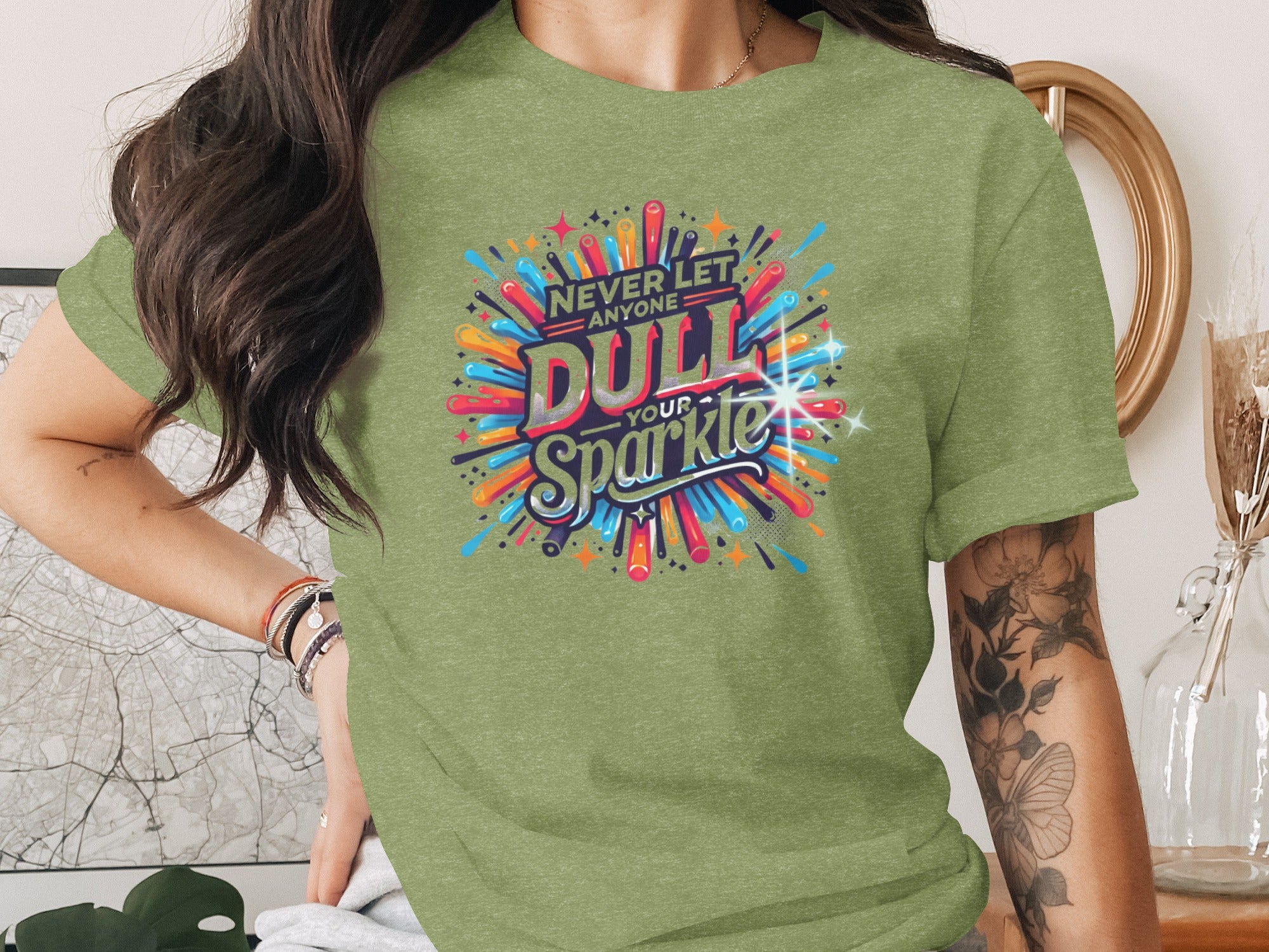 Green t-shirt with text "NEVER LET ANYONE DULL YOUR Sparkle" in colorful retro design.
