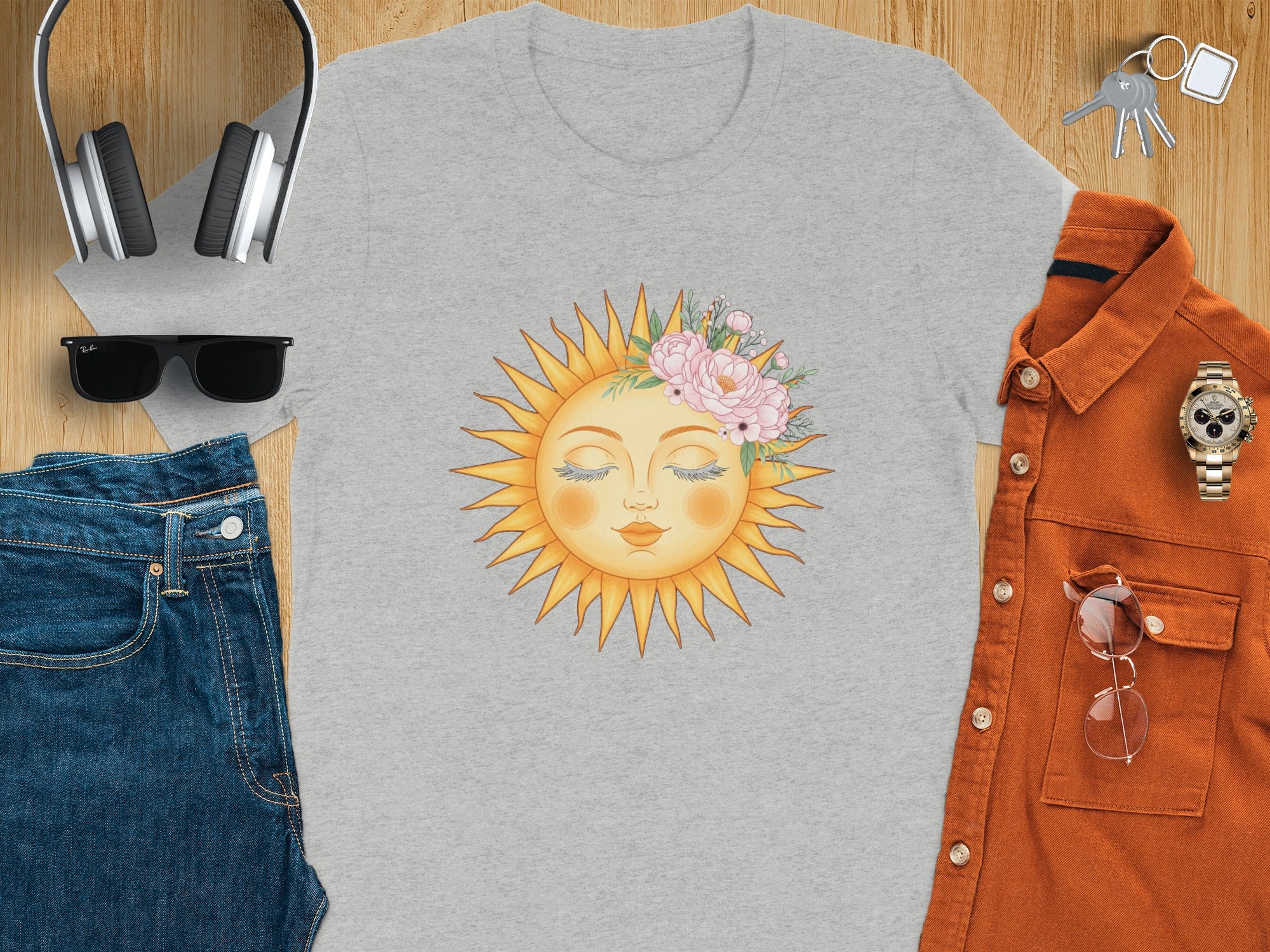 Grey t-shirt with a sun face adorned with pink flowers and green leaves.