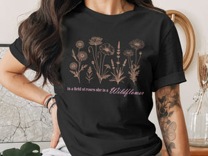 Black t-shirt with a floral line art print and the text "in a field of roses she is a Wildflower."