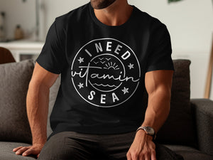 Black t-shirt with "I Need Vitamin Sea" design and sun, waves, and birds.