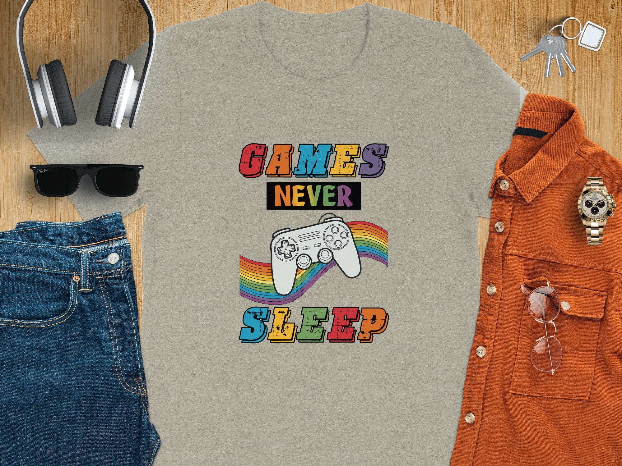 Grey t-shirt with 'GAMES NEVER SLEEP' text, a gamepad, and rainbow graphic.