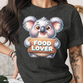 Cute koala holding a sign that says "FOOD LOVER" on a dark t-shirt.