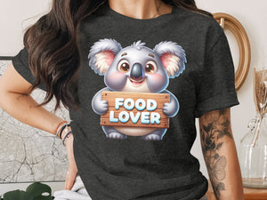 Cute koala holding a sign that says "FOOD LOVER" on a dark t-shirt.
