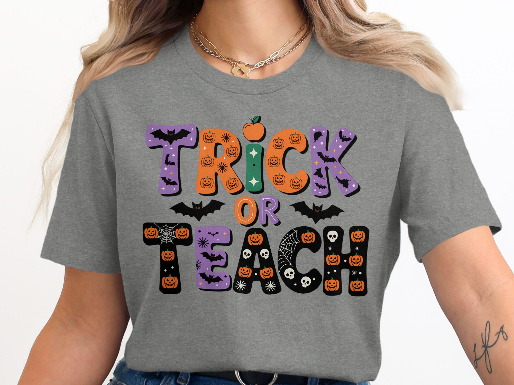 Grey t-shirt with "Trick or Teach" Halloween text design featuring pumpkins, bats, and skulls.