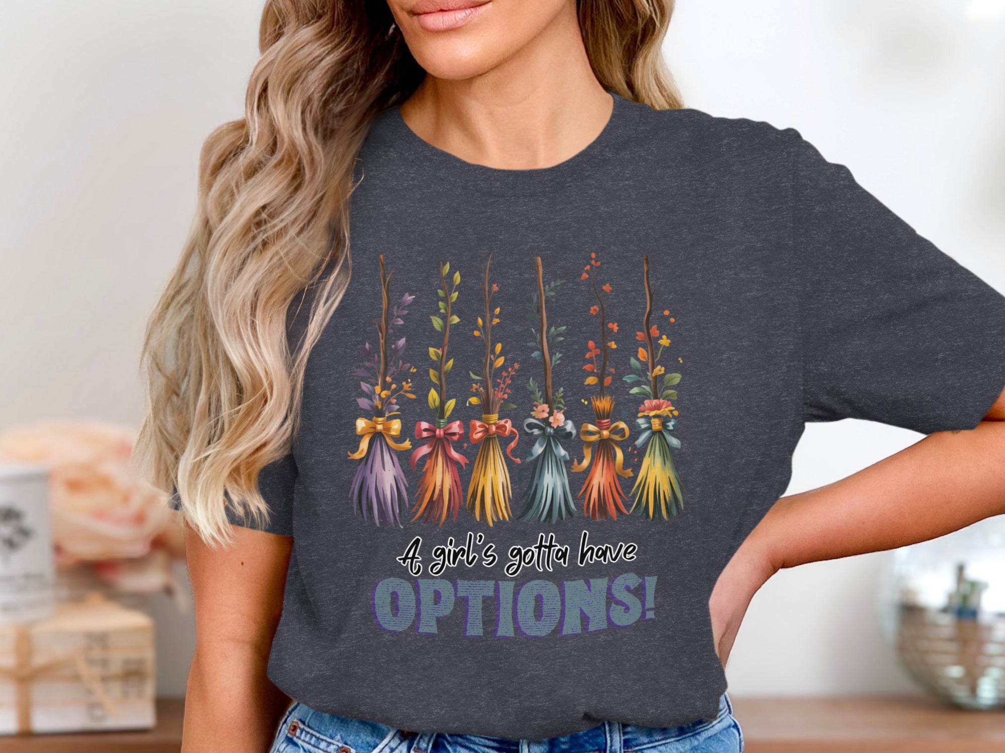 Dark t-shirt with a graphic of five decorative brooms and the text "A girl's gotta have OPTIONS!"