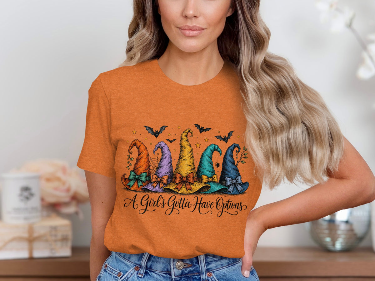 Orange t-shirt with five colorful witch hats and bats. "A Girl's Gotta Have Options" text.