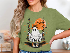 Ghost on a swing with orange moon and bats on Halloween-themed shirt.