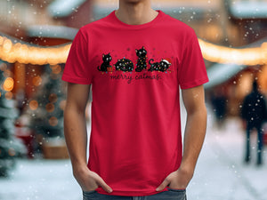 Red t-shirt with cartoon black cats tangled in Christmas lights and "merry catmas." text.
