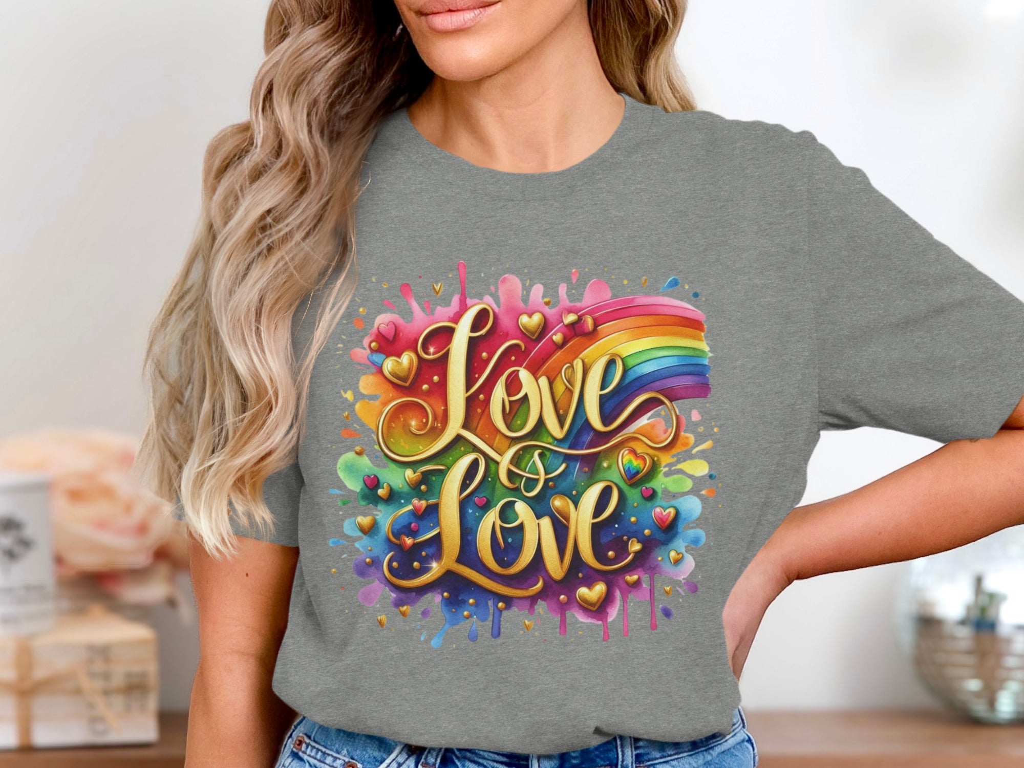 Golden text "Love is Love" with rainbow and hearts on a gray t-shirt.