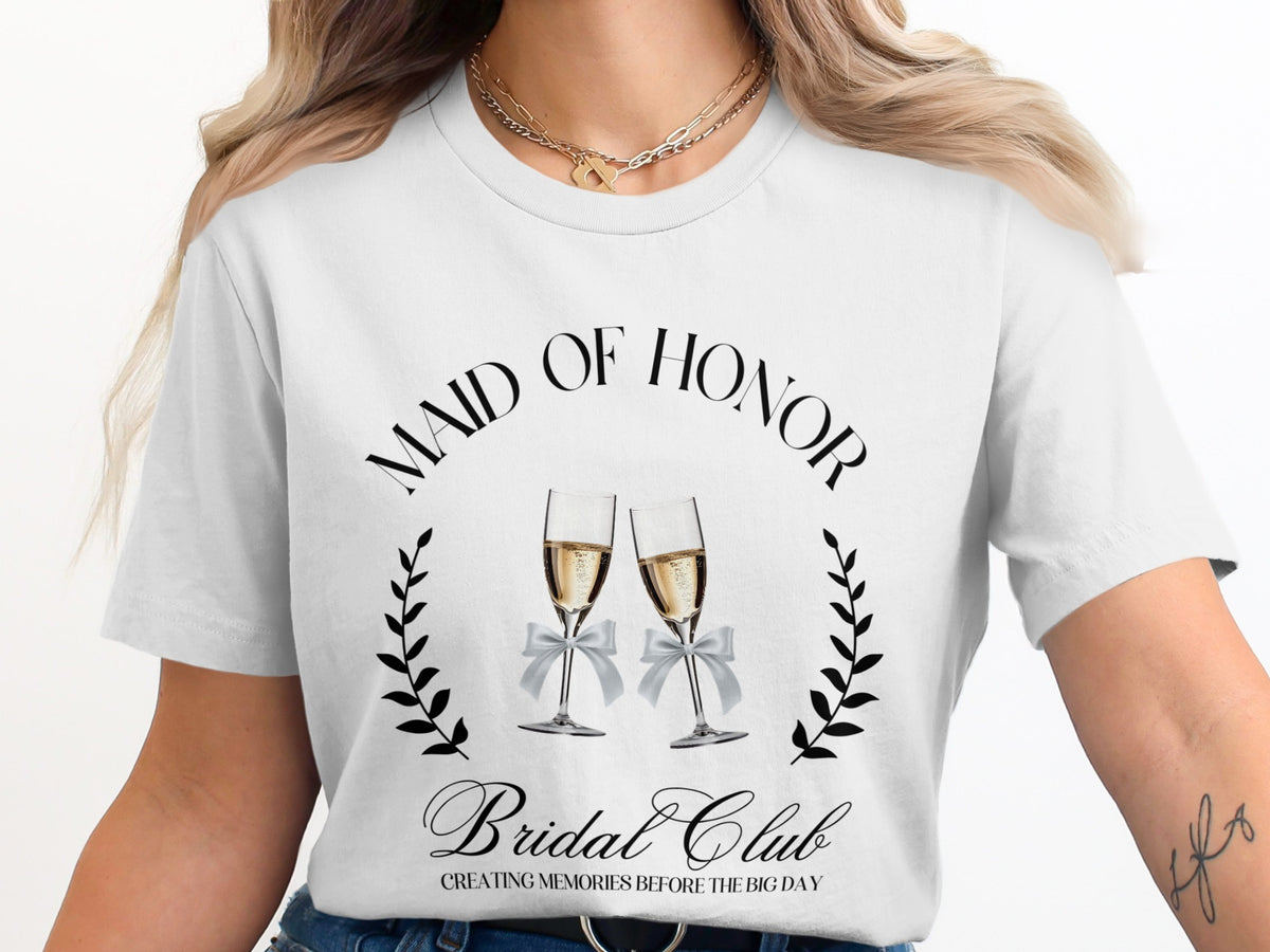 White t-shirt with "Maid of Honor" and "Bridal Club" text, champagne glasses, and laurels.