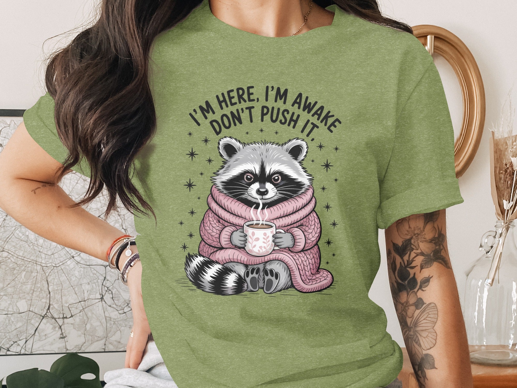 Green t-shirt with raccoon illustration and text "I'm here, I'm awake, don't push it."