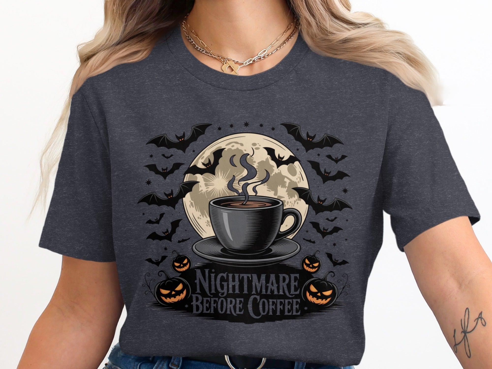 Dark t-shirt graphic with steaming coffee cup, moon, bats, pumpkins, and text "Nightmare Before Coffee".