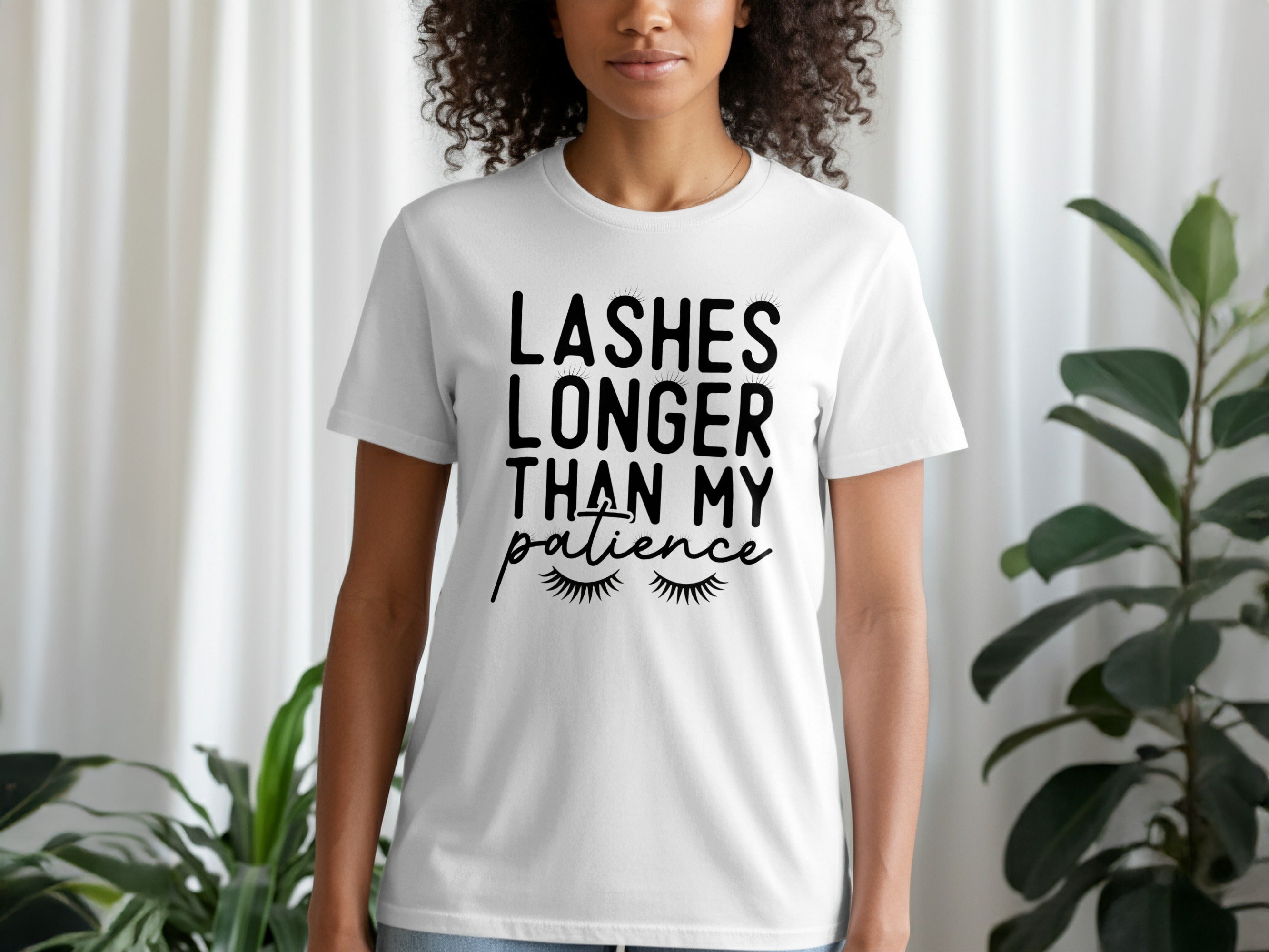 White t-shirt with black text and eyelash graphics that read "Lashes Longer Than My Patience".