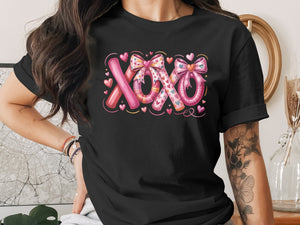 Black t-shirt with "XOXO" text design with hearts and bows.