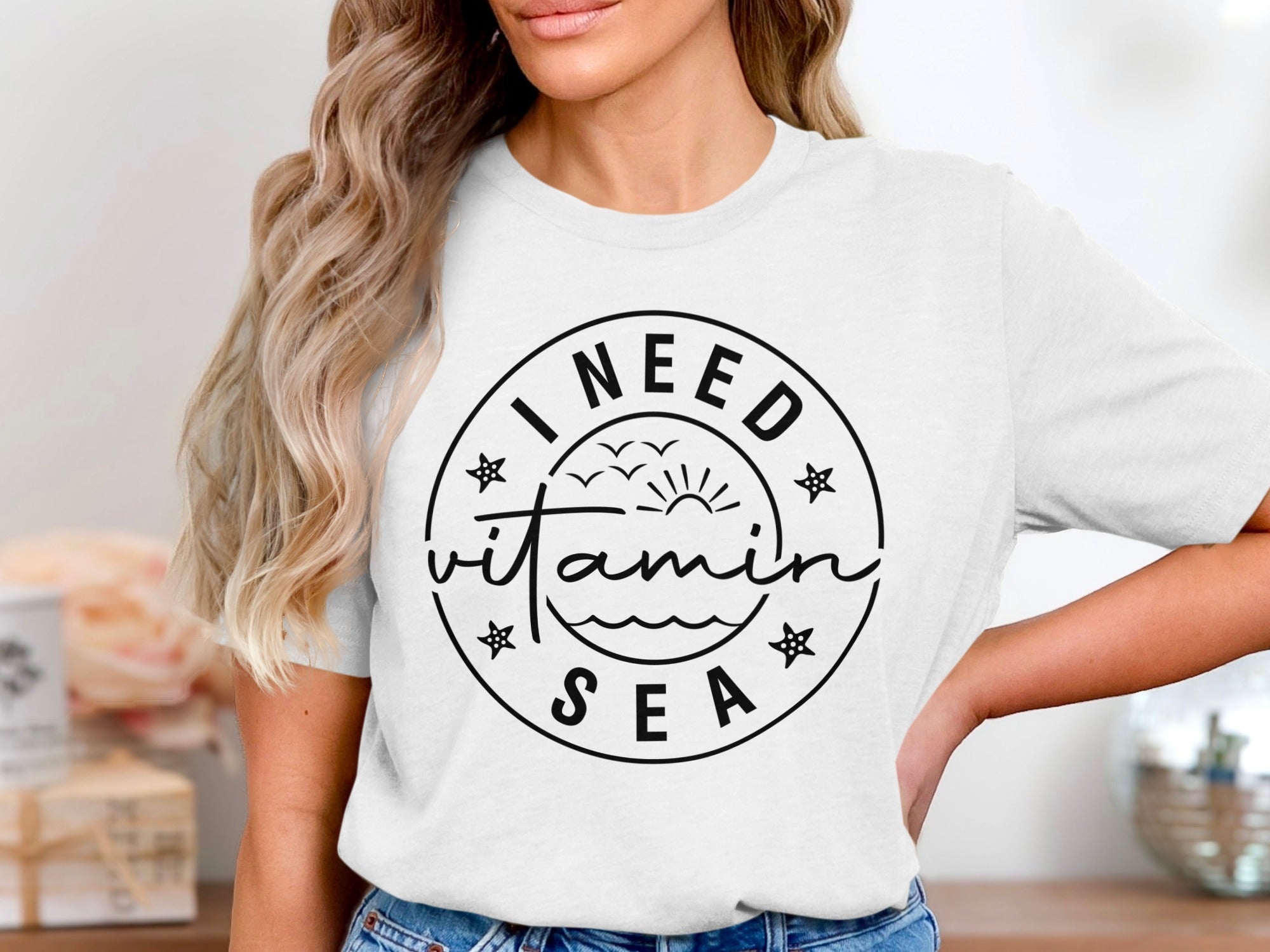 White t-shirt with "I NEED vitamin SEA" graphic in black circle
