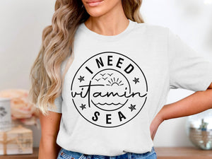 White t-shirt with "I NEED vitamin SEA" graphic in black circle
