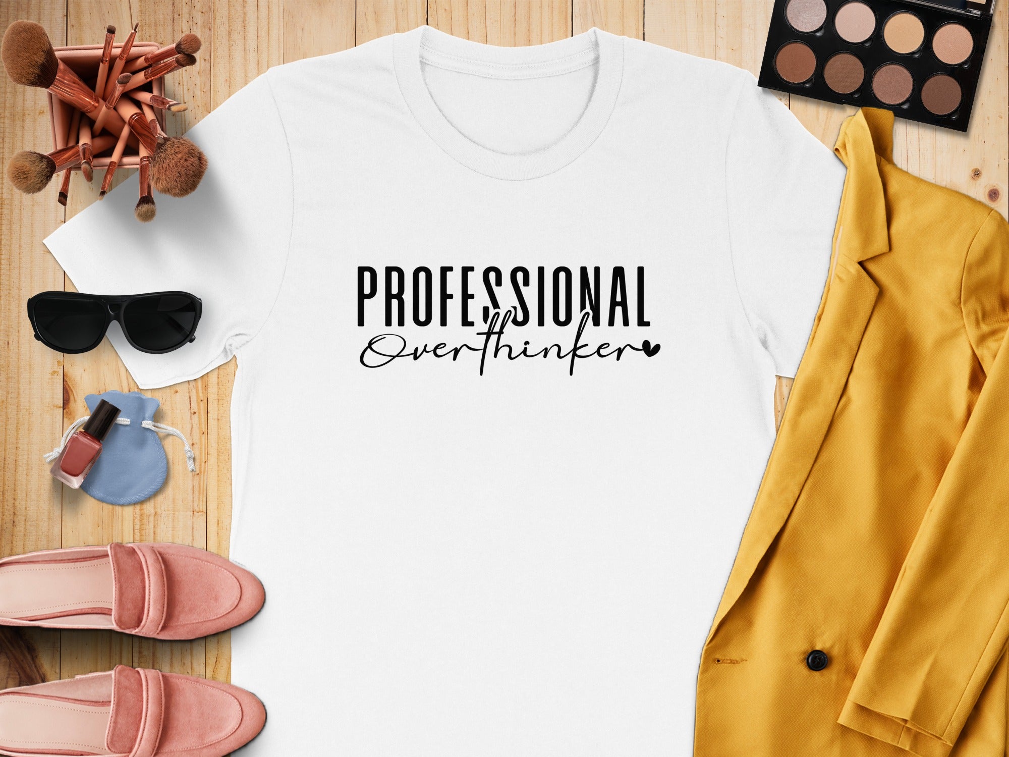 White t-shirt with "PROFESSIONAL Overthinker" text, surrounded by makeup and clothing items.
