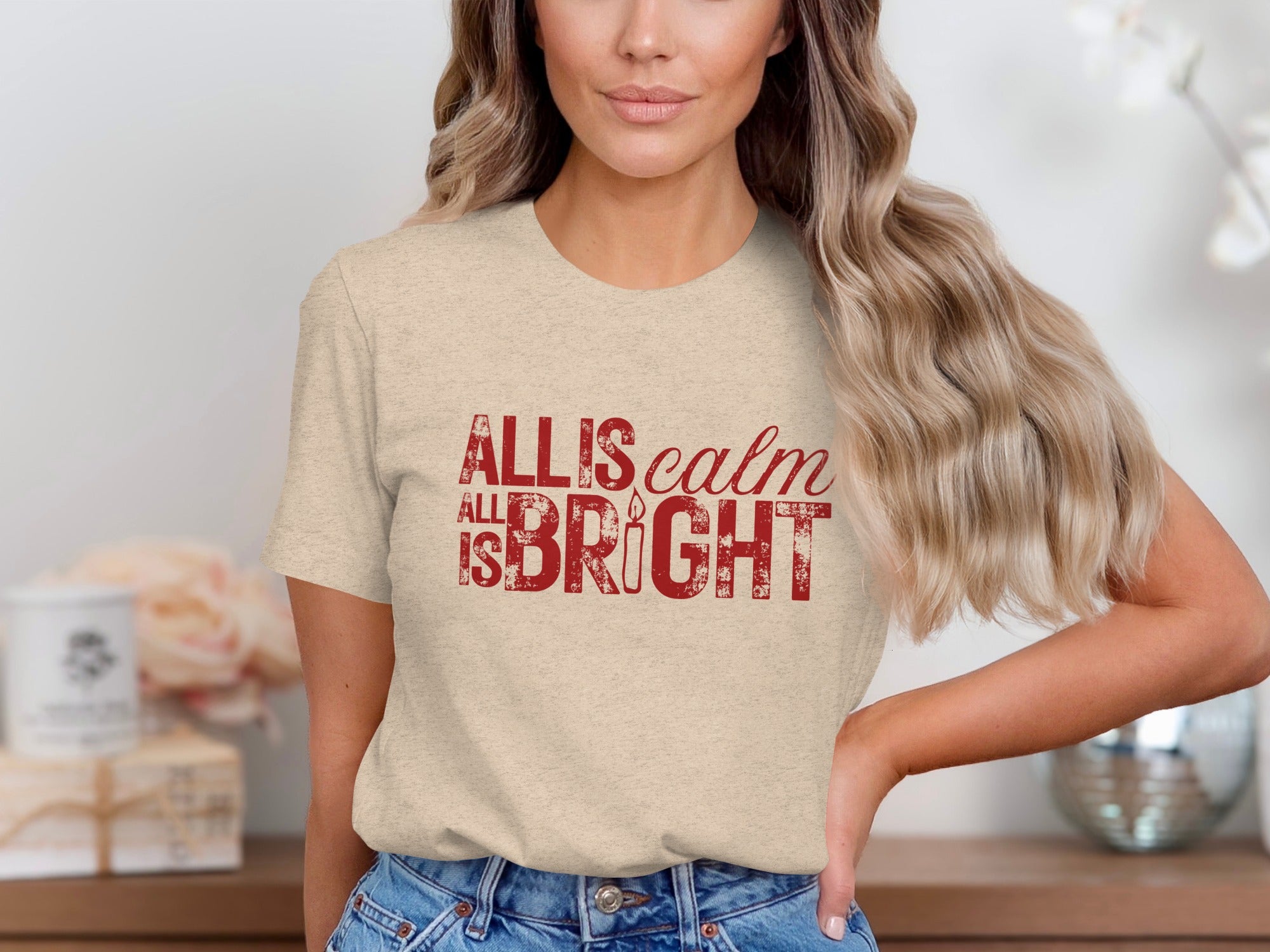 Light beige t-shirt with red distressed text reading "ALL IS calm ALL IS BRIGHT" and a candle.