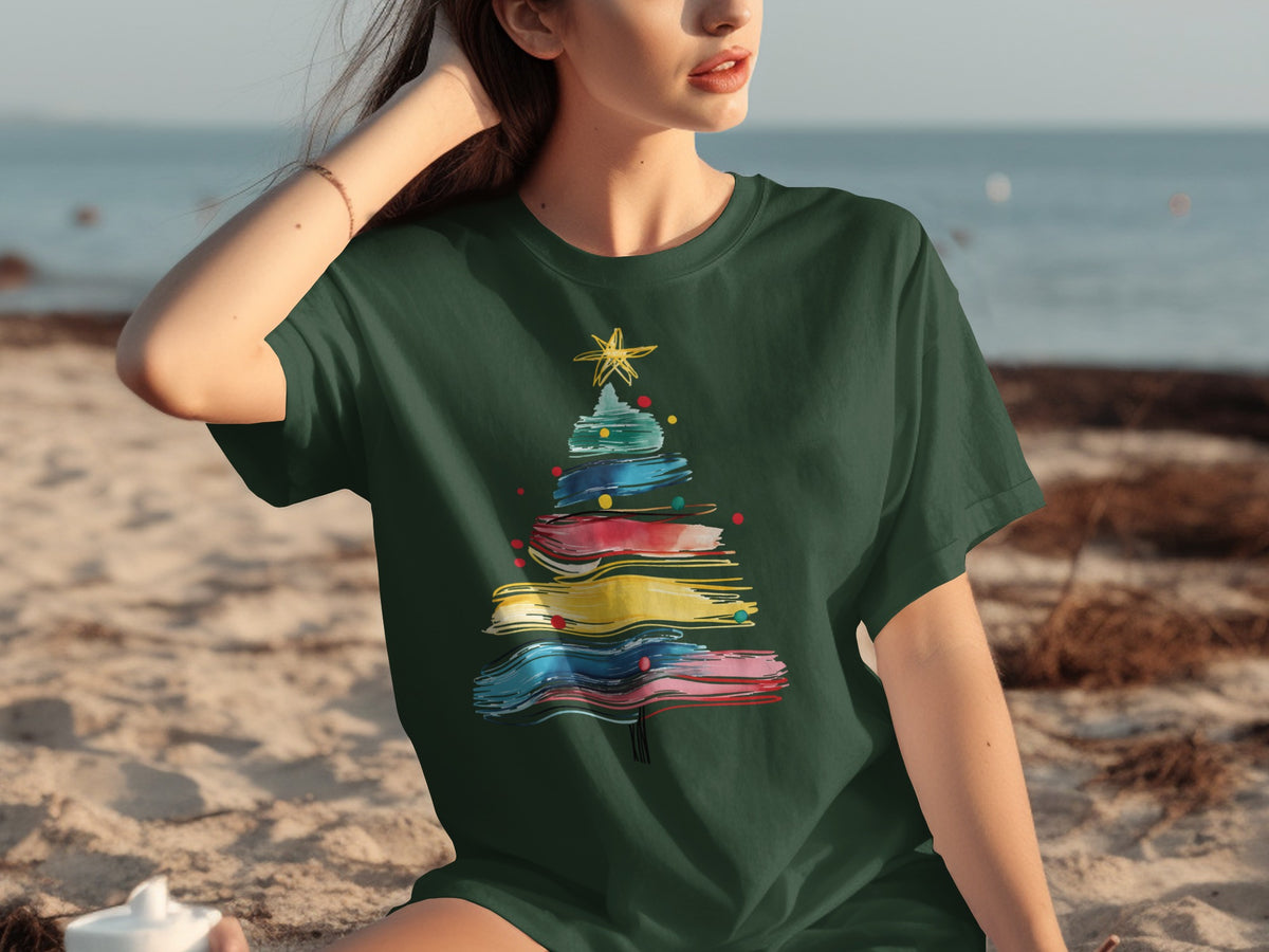 Dark green t-shirt with colorful abstract Christmas tree print on beach.