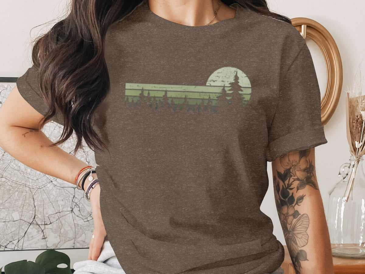 Brown t-shirt with green sunset and pine trees graphic design.