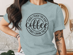 Light blue t-shirt with black circular text: "First I drink the coffee, then I teach the kids."