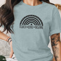 Light blue t-shirt with black rainbow graphic and "TEACH LOVE INSPIRE" text.