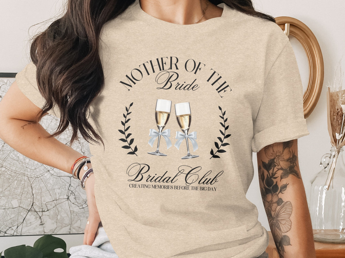 Mother of the Bride Bridal Club text with champagne glasses graphic on a tan shirt.