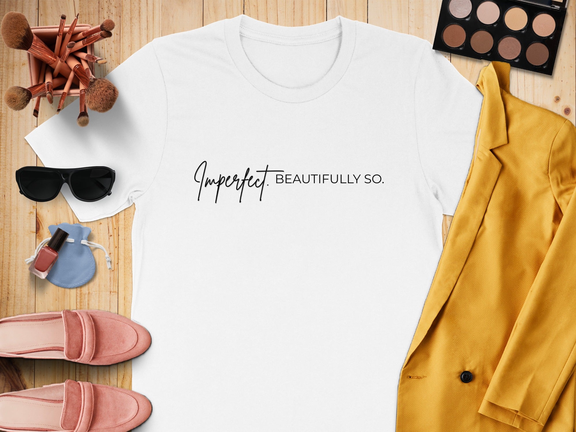 White t-shirt with "Imperfect Beautifully So." text, flat lay with makeup and clothing.
