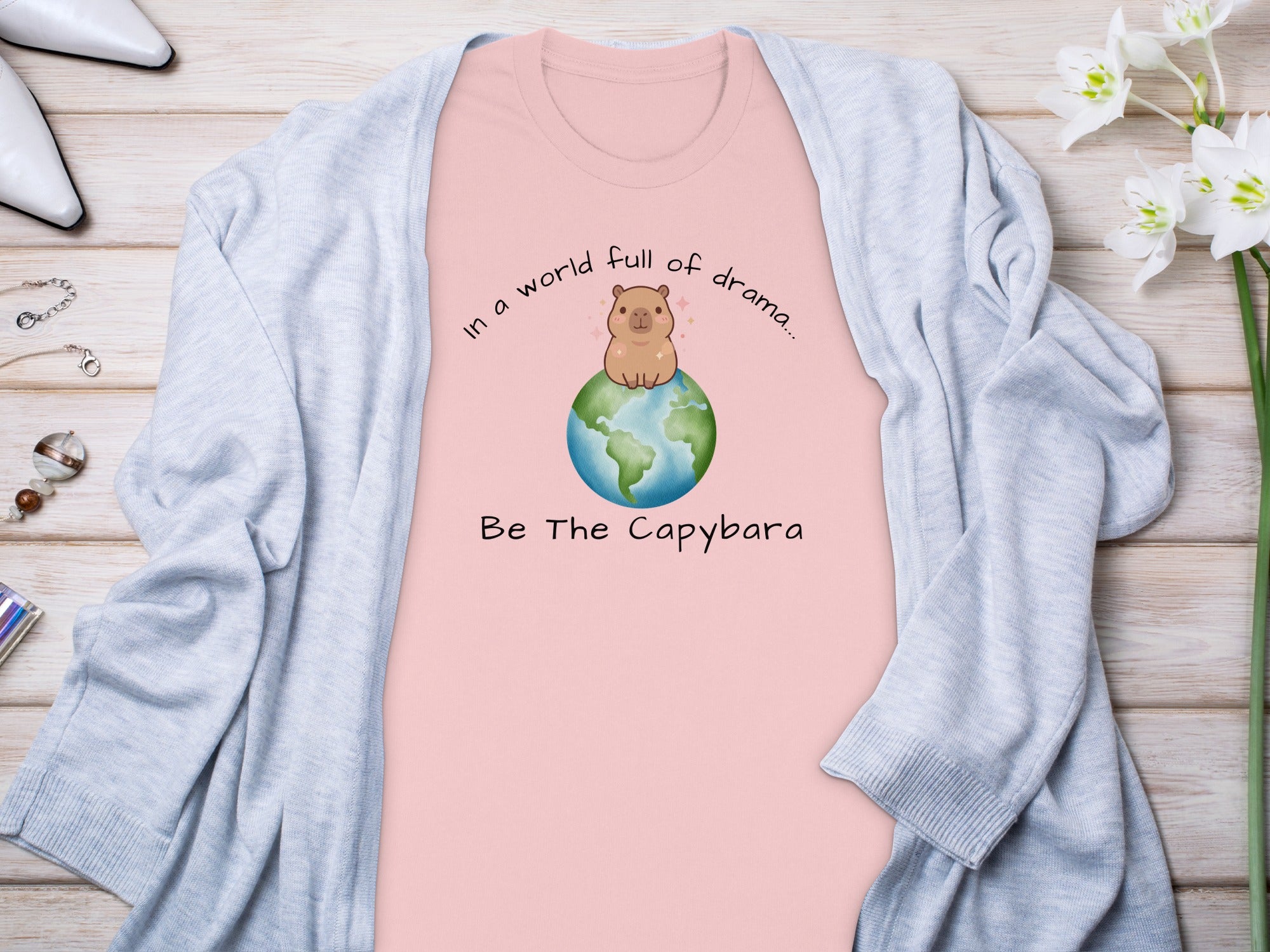 Pink t-shirt with a capybara on Earth and text "Be The Capybara".