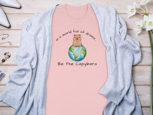 Pink t-shirt with a capybara on Earth and text "Be The Capybara".