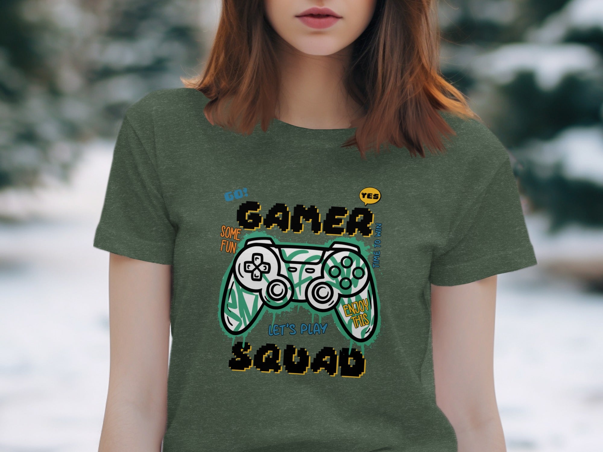 Green t-shirt with "GAMER SQUAD" graphic featuring a video game controller, "GO!", "YES", "SOME FUN", "TIME TO WIN", "ENJOY THIS", and "LET'S PLAY".