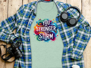 Light green t-shirt with "YOU ARE STRONGER THAN THE STORM" graphic and open plaid shirt.
