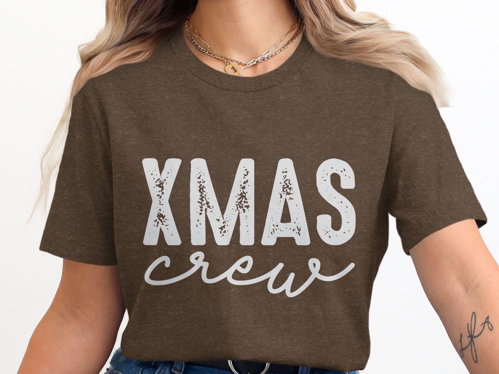 Brown t-shirt with white "XMAS crew" graphic and layered necklaces.