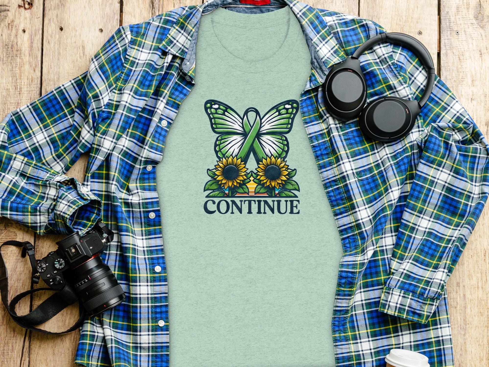 Light green t-shirt with butterfly, sunflowers, and "CONTINUE" text design.