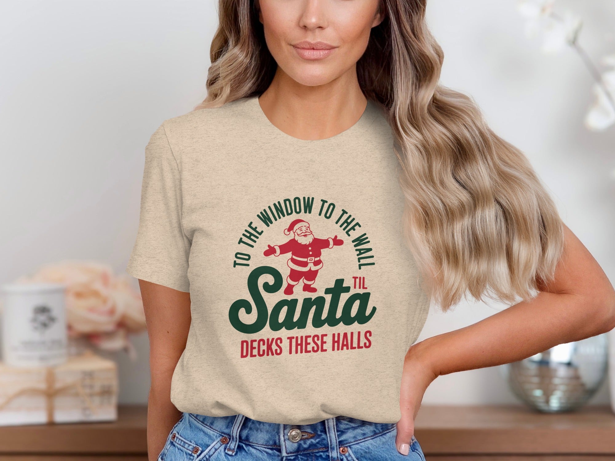 Light beige t-shirt with graphic "TO THE WINDOW TO THE WALL 'TIL SANTA DECKS THESE HALLS."