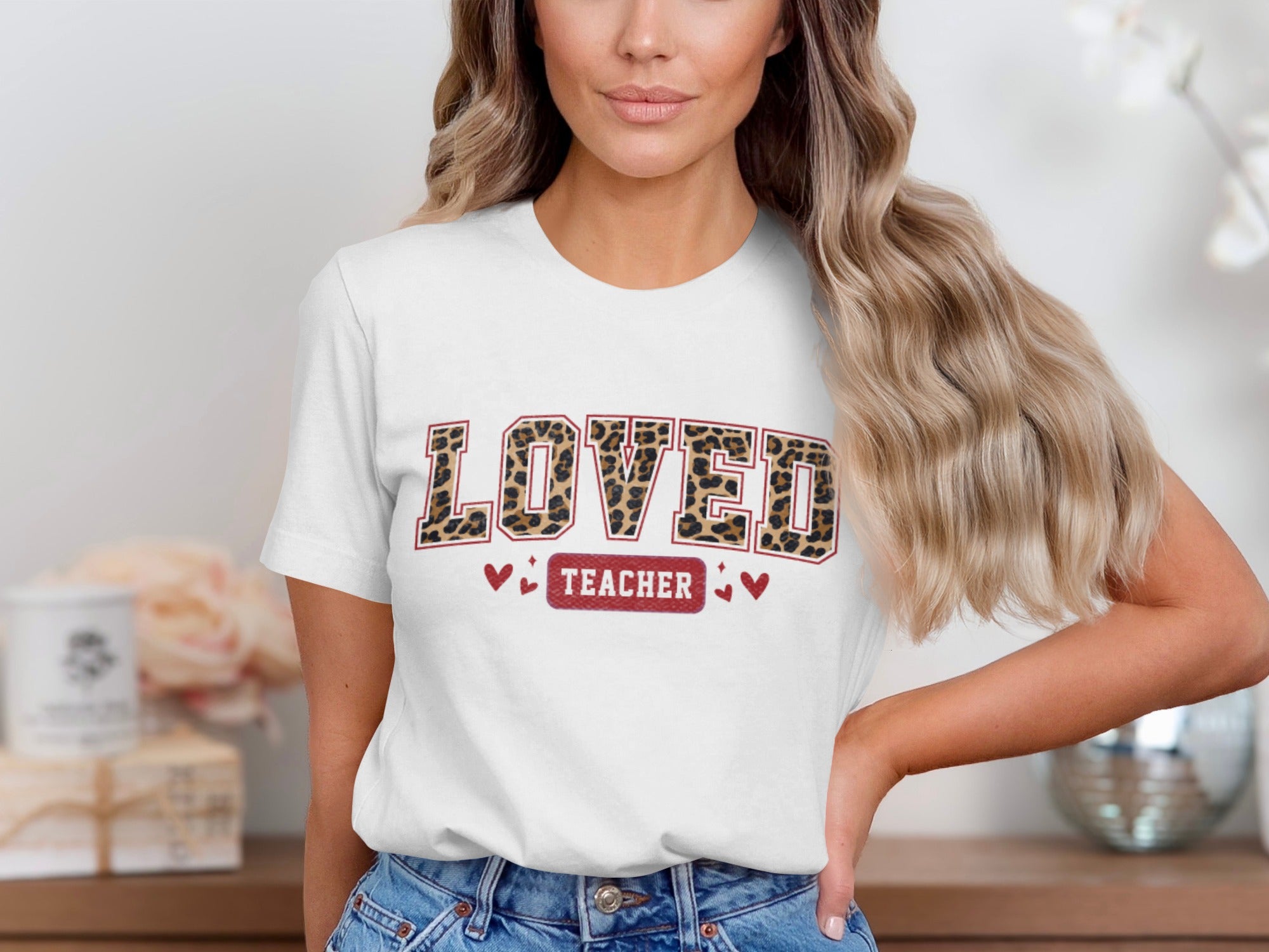White t-shirt with leopard print text "LOVED TEACHER" and small hearts.