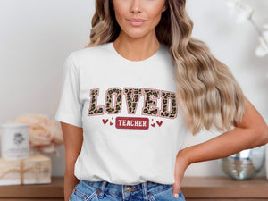 White t-shirt with leopard print text "LOVED TEACHER" and small hearts.