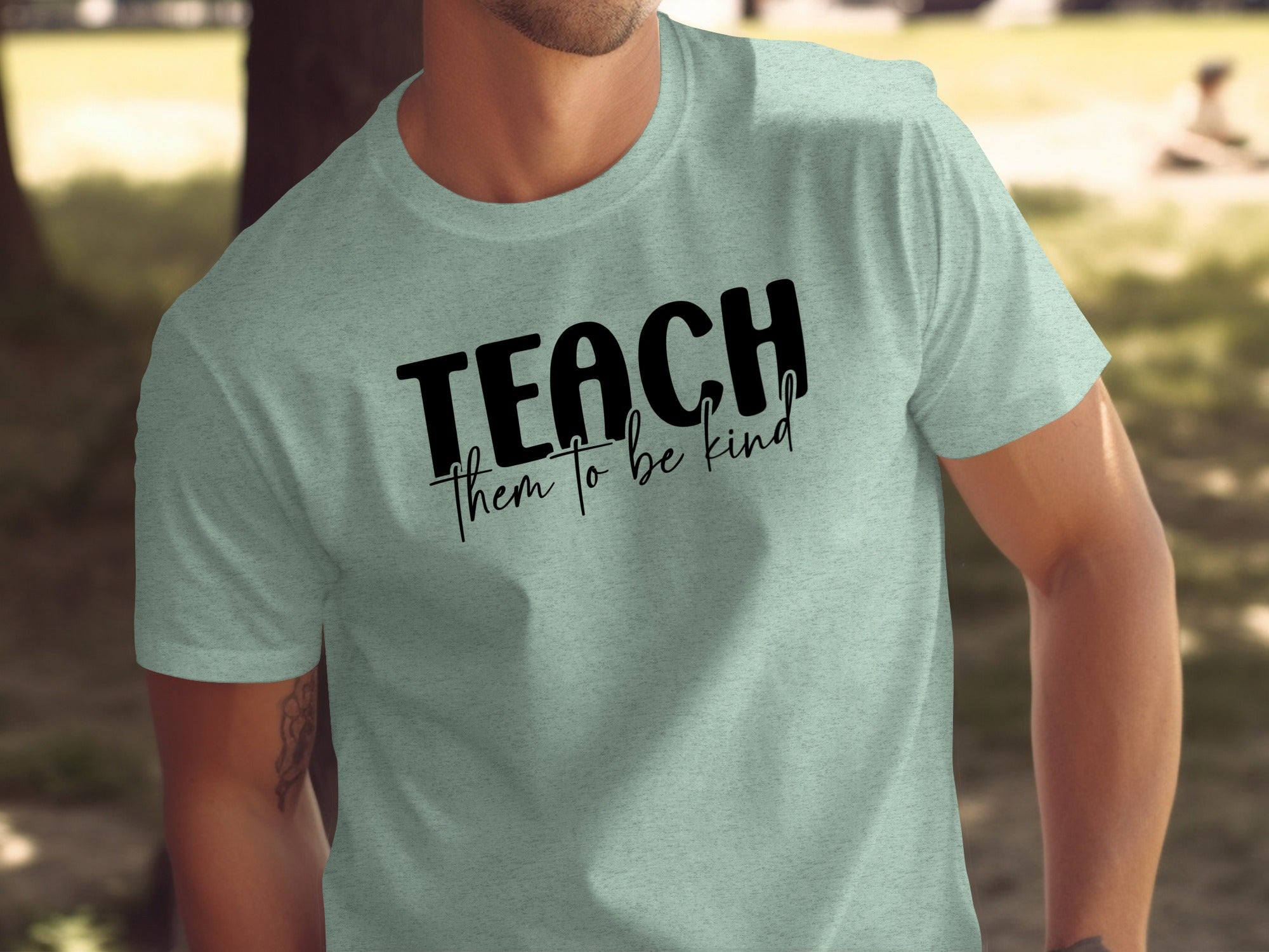 Light blue t-shirt with black text that reads "TEACH them to be kind"