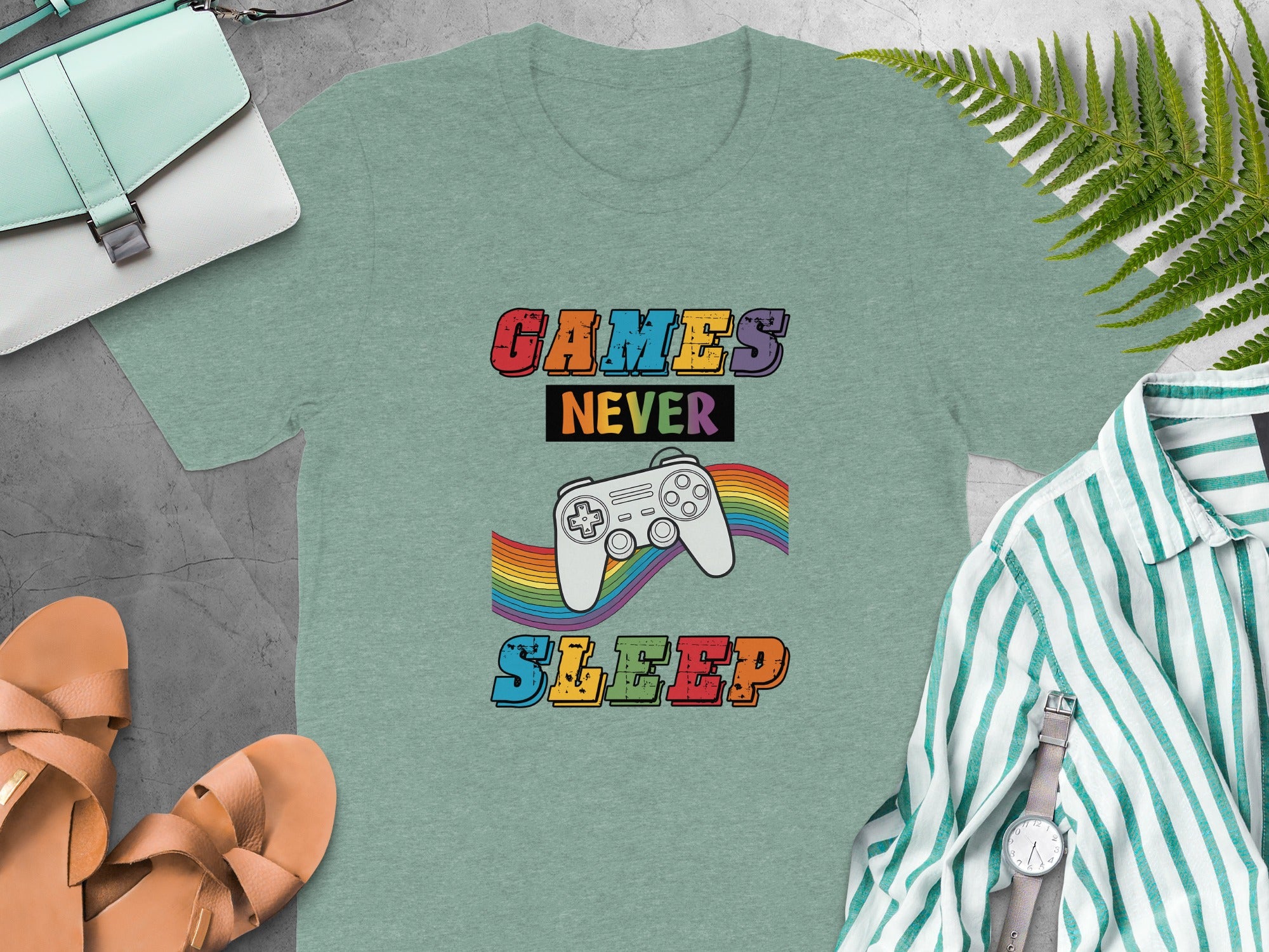 Green t-shirt with "GAMES NEVER SLEEP" text and a video game controller with a rainbow.