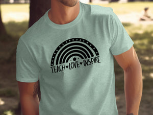 Light sage t-shirt with black rainbow graphic and "TEACH LOVE INSPIRE" text.
